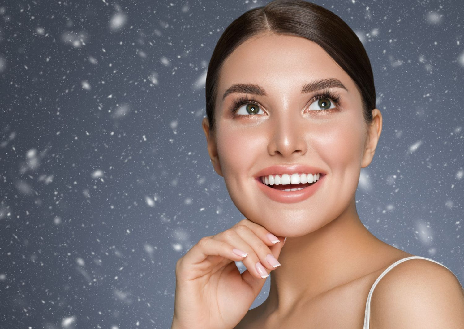 A close up of a woman 's face with snow falling in the background.