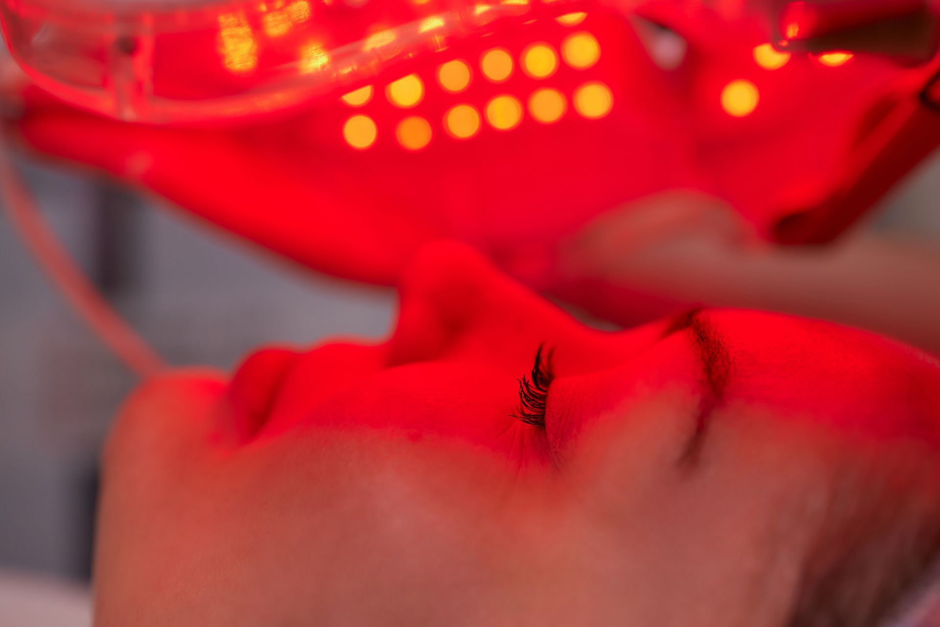 A woman is getting a red light treatment on her face.