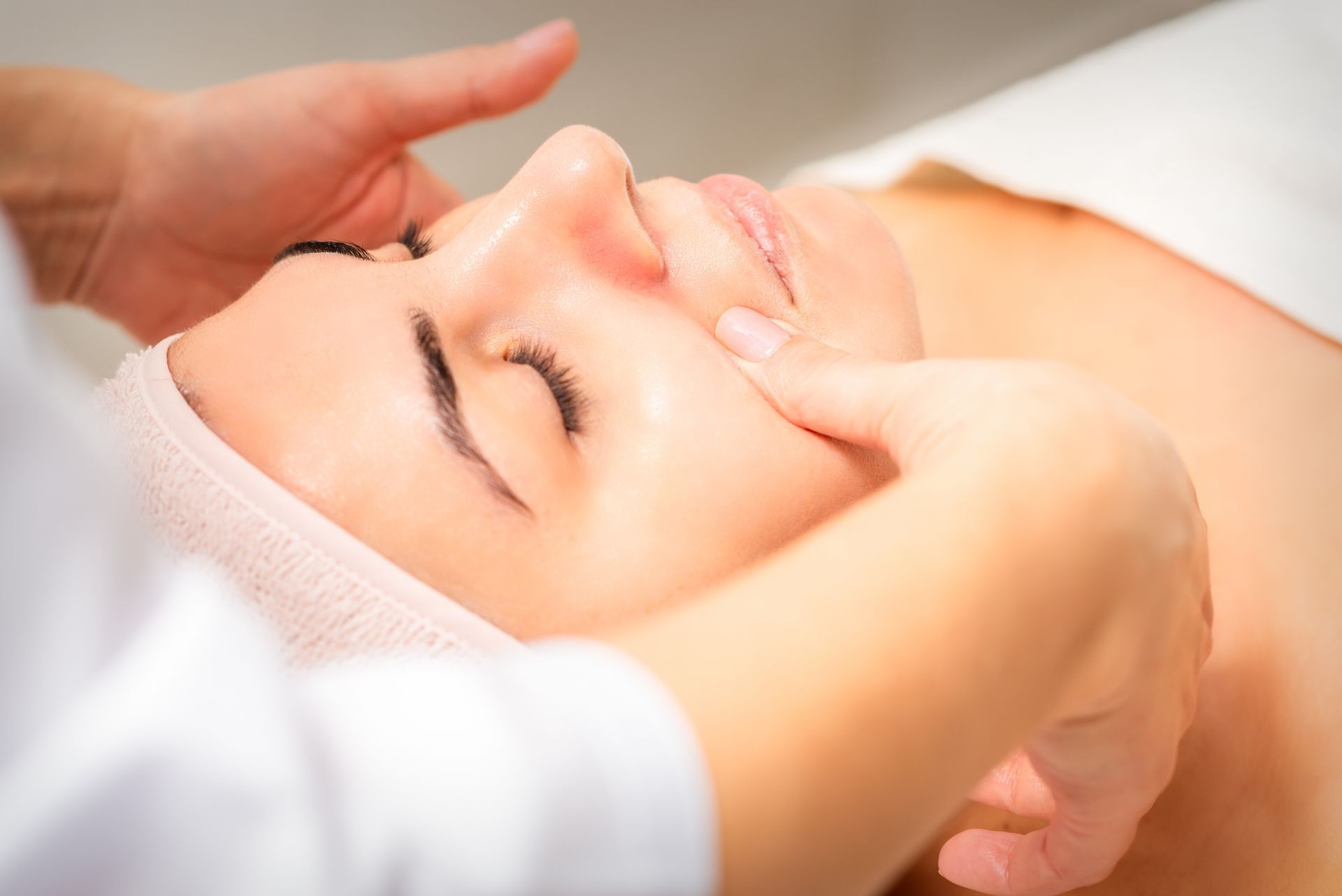 A woman is getting a facial massage at a spa.