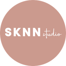 A pink circle with the words sknn studio written inside of it.