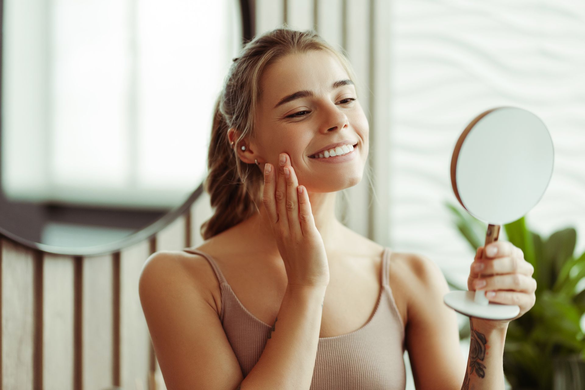 Smiling person looking in a mirror while applying white toothpaste with a toothbrush