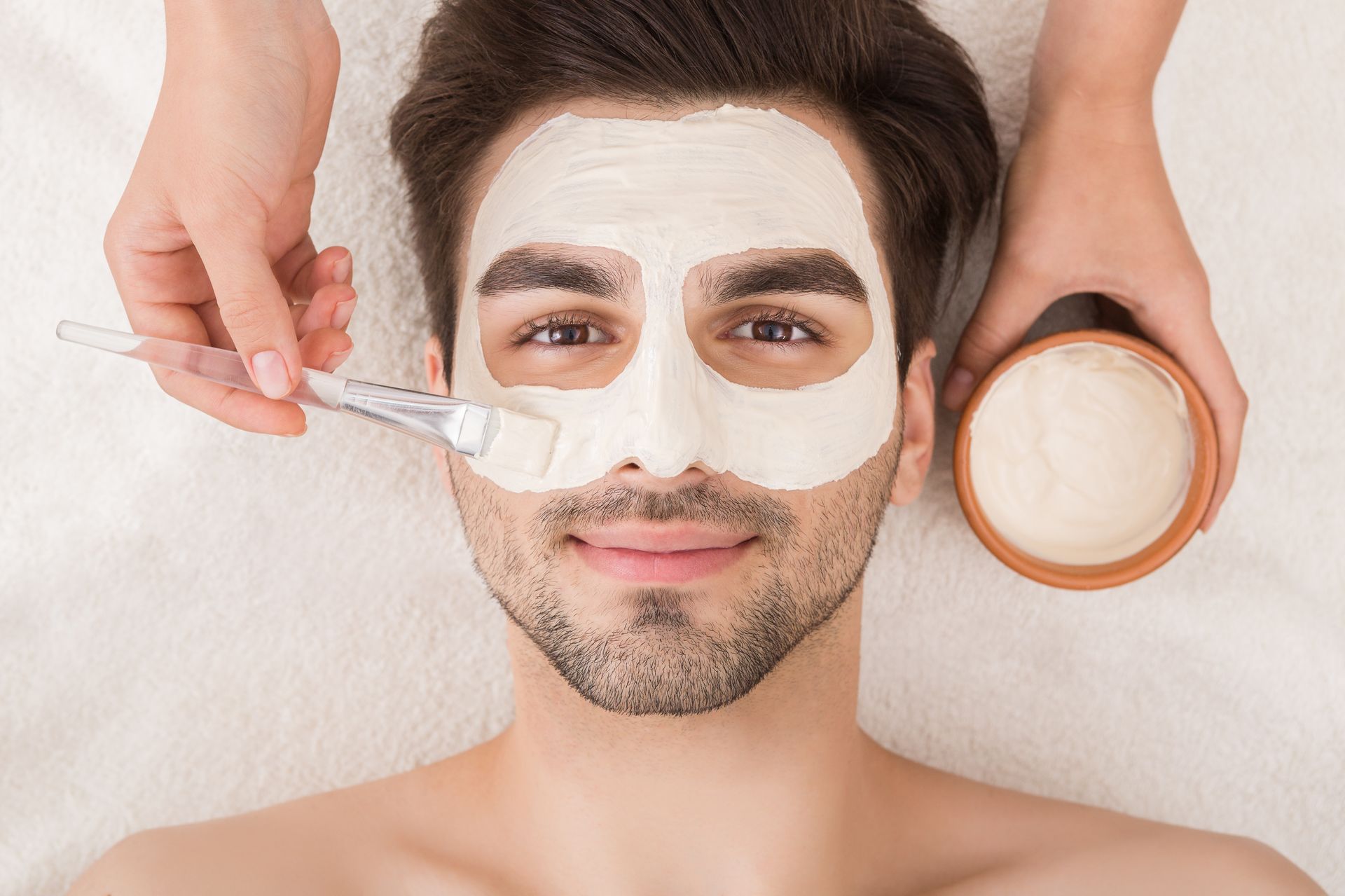 A man is getting a facial mask at a spa.