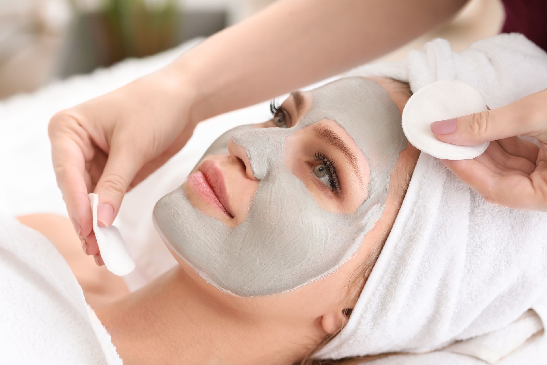 A woman is getting a clay mask on her face at a spa.