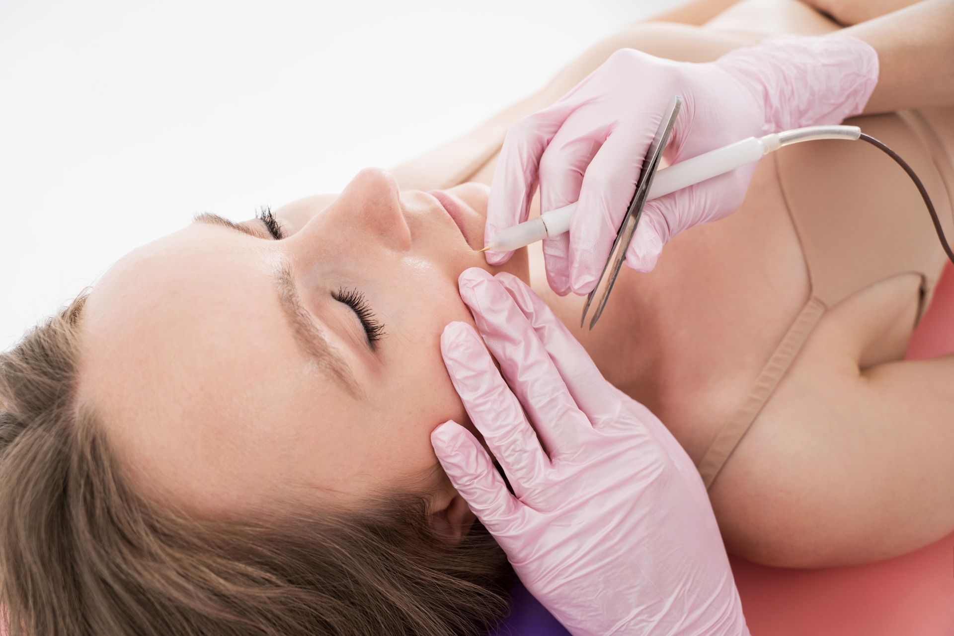 Cosmetic procedure on woman’s face with gloved hands and syringe, close-up in a clinical setting