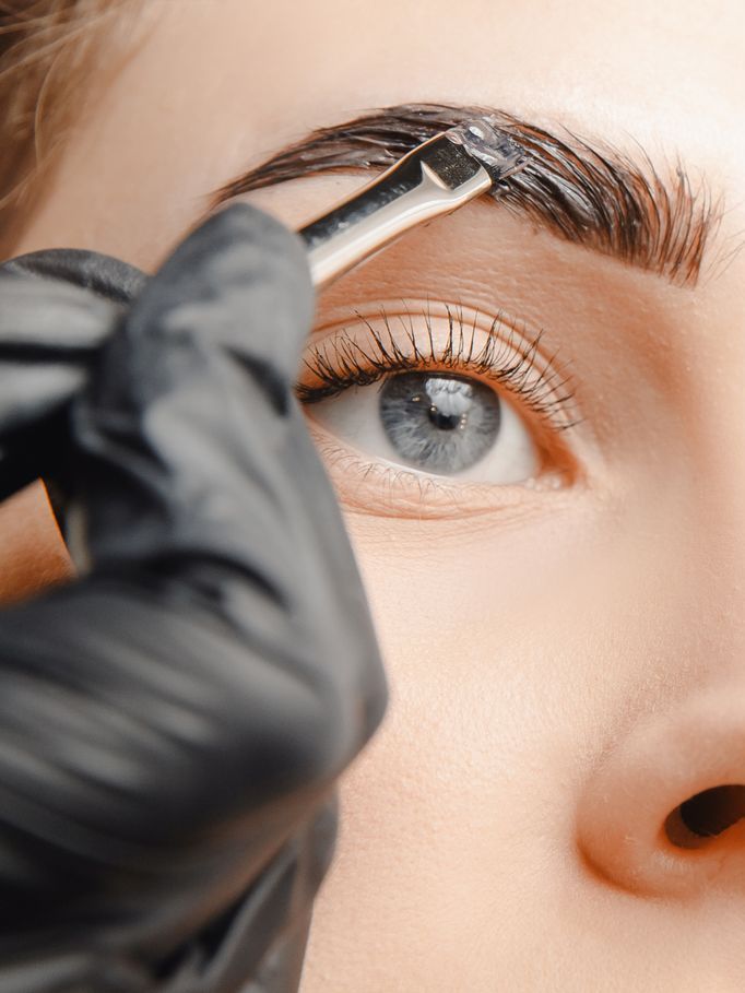 A woman is getting her eyebrows painted with a brush.