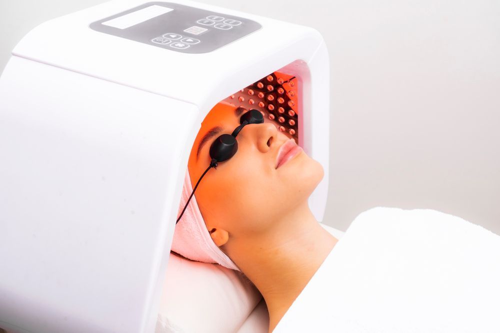 A woman is getting a light therapy treatment on her face.