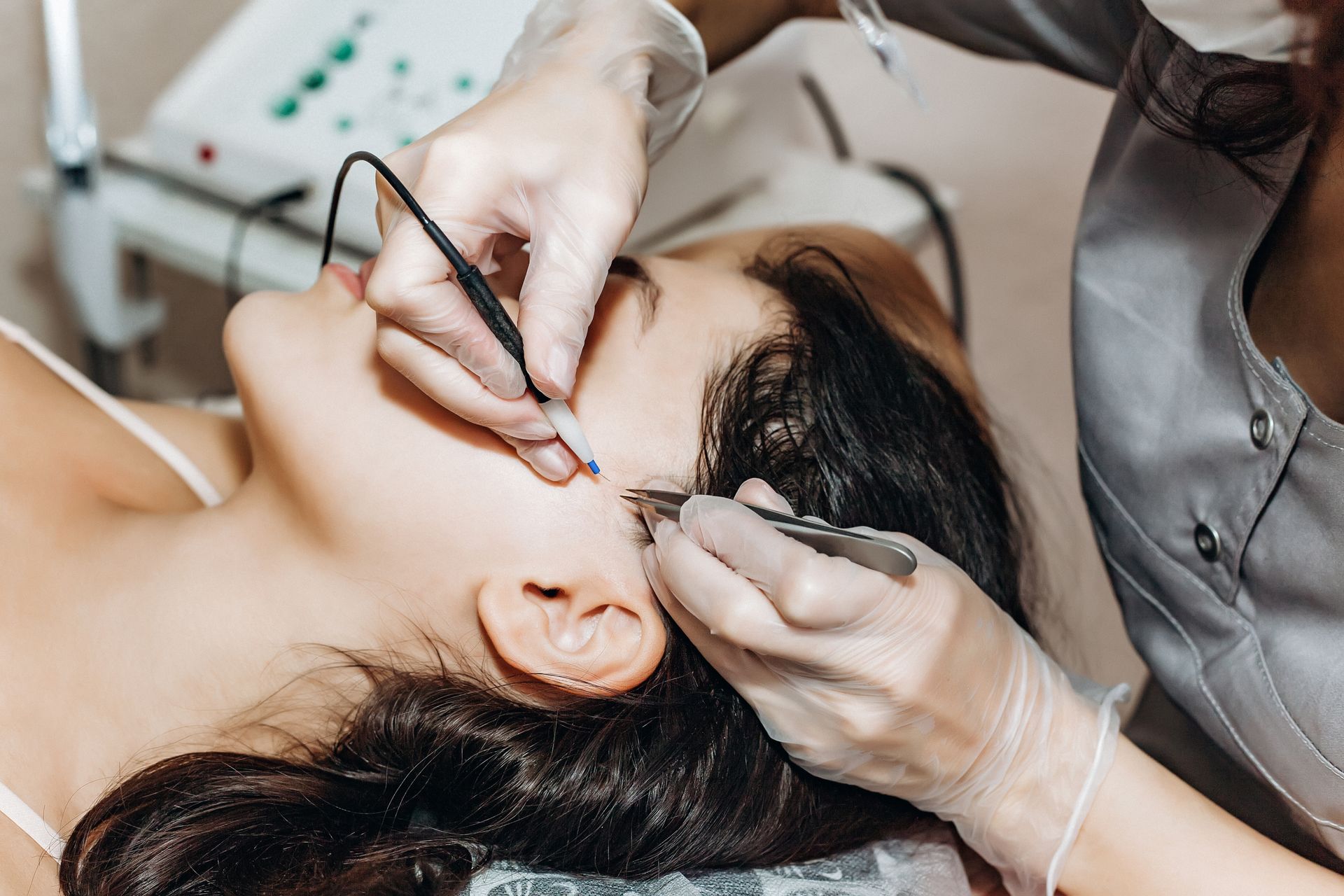 A woman is getting a tattoo on her eyebrows in a beauty salon.