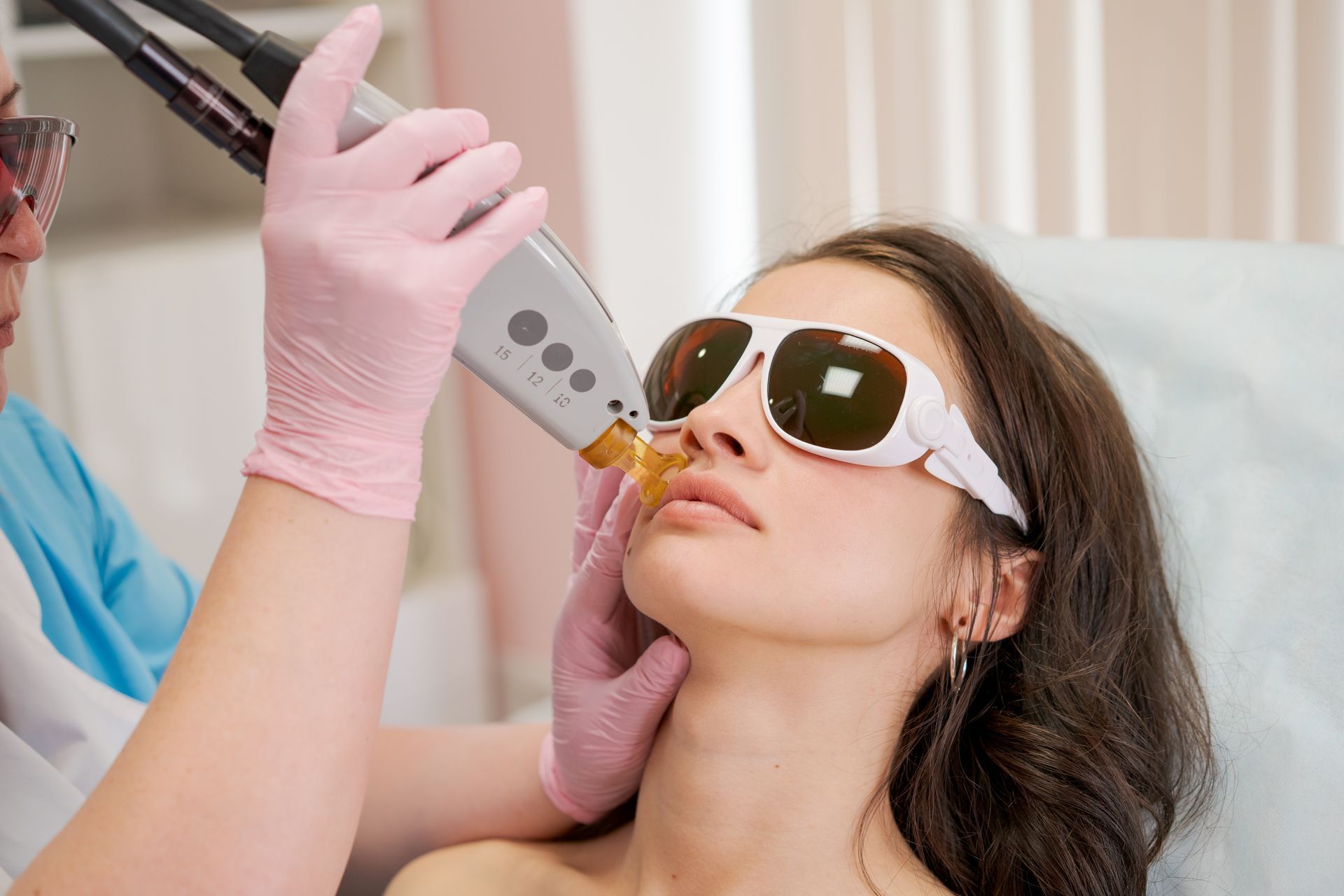 A woman is getting a laser hair removal treatment on her face.