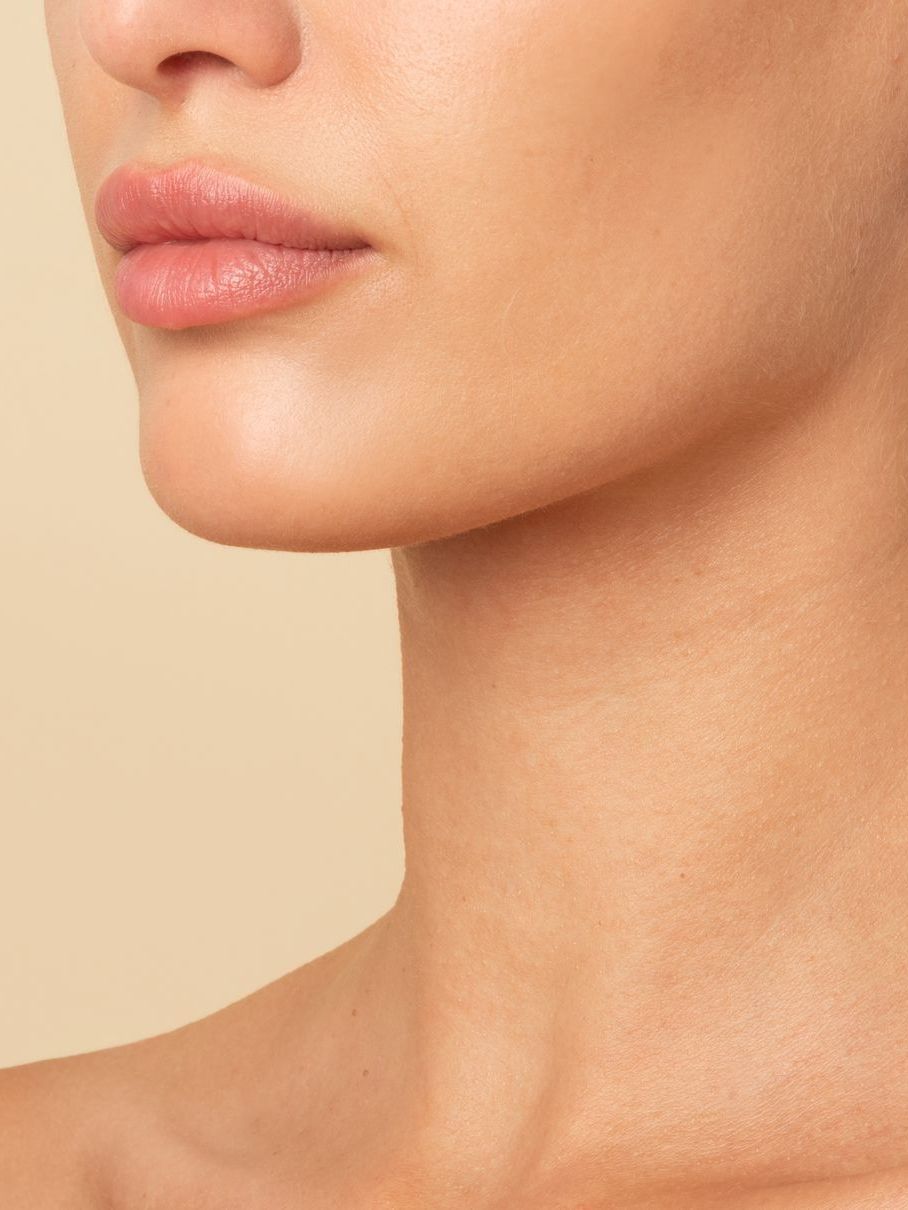 A close up of a woman 's neck and face on a beige background.
