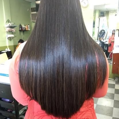 Woman with long, straight, shiny dark brown hair; in a salon.