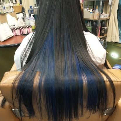 Woman with long black hair, blue highlights at the ends, in a salon chair.