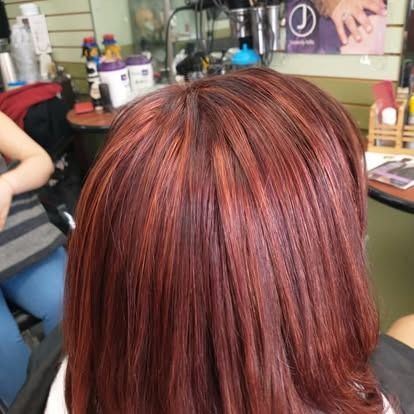 Close-up of red hair with auburn highlights in a salon setting.
