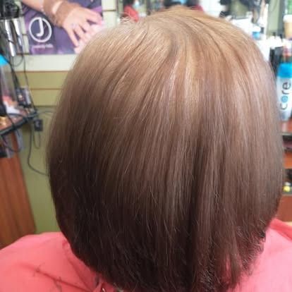 Woman with brown ombre-style hair, a light top, and a salon setting.