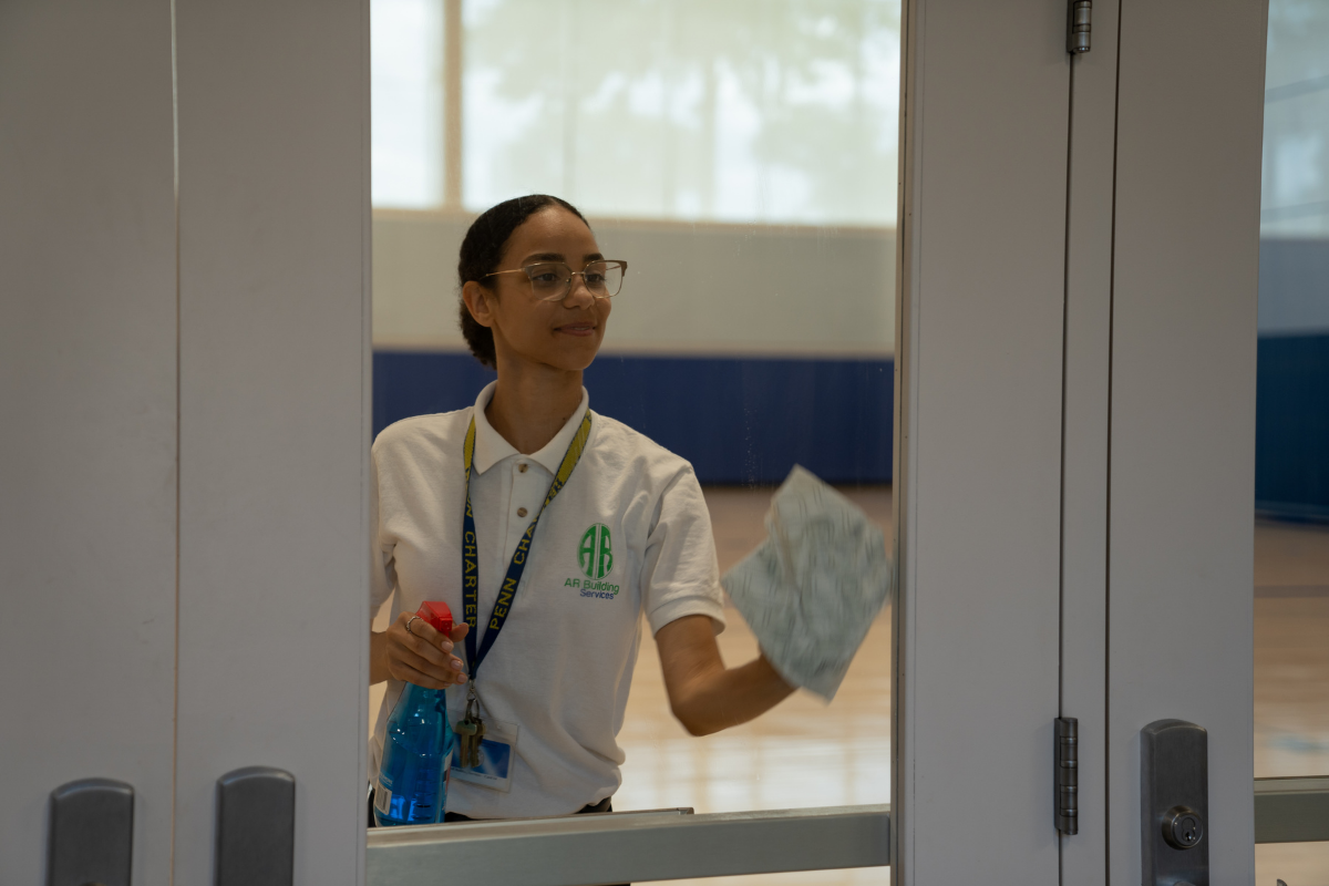A woman is cleaning a window with a mop in an office.