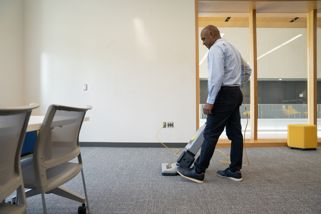 A person is cleaning a carpet with a vacuum cleaner.