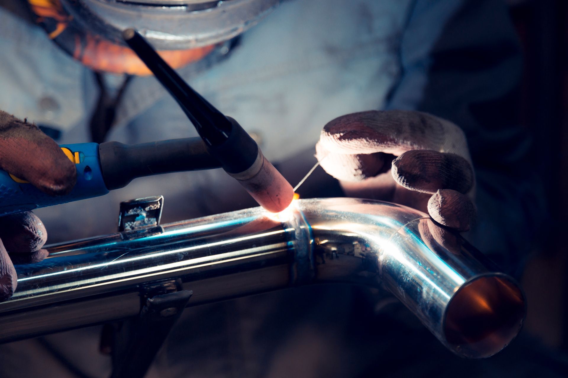 Soudeur travaillant sur un joint de tuyau métallique brillant avec une torche et des gants de protection