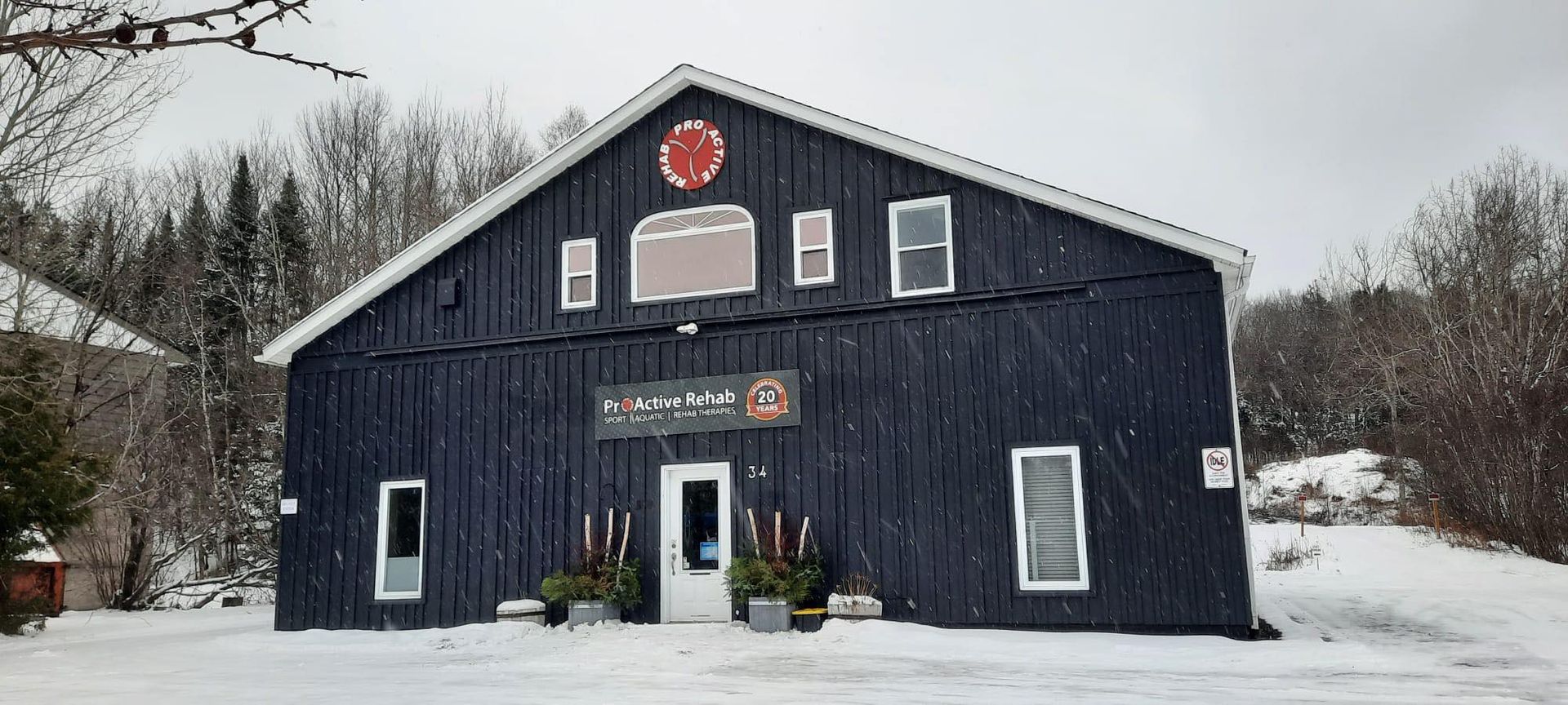 A dark blue, barn-style building with white trim, featuring a central entrance, several windows, and a red circular sign.