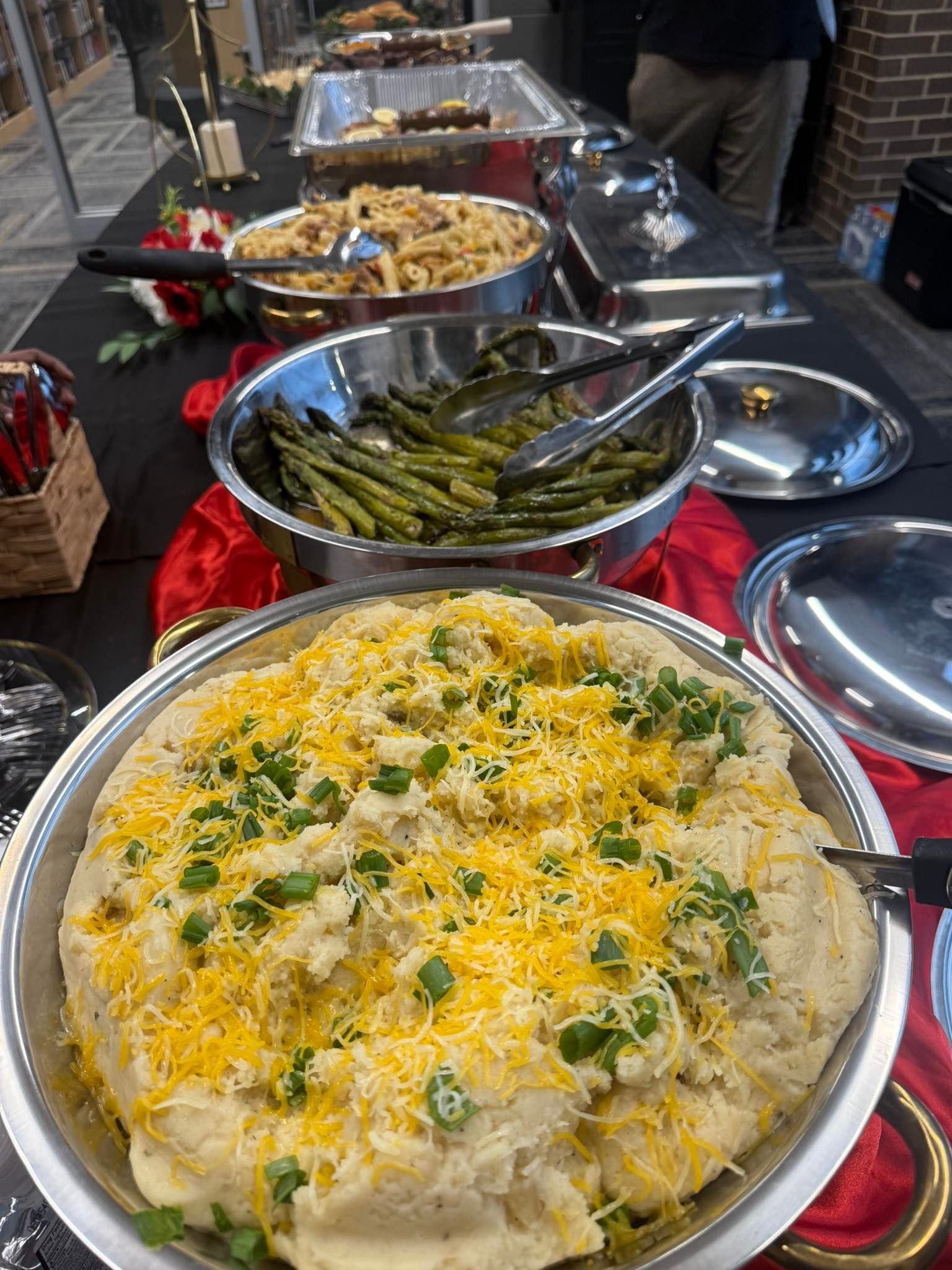 Buffet spread: mashed potatoes with cheese, asparagus, pasta, and other dishes.