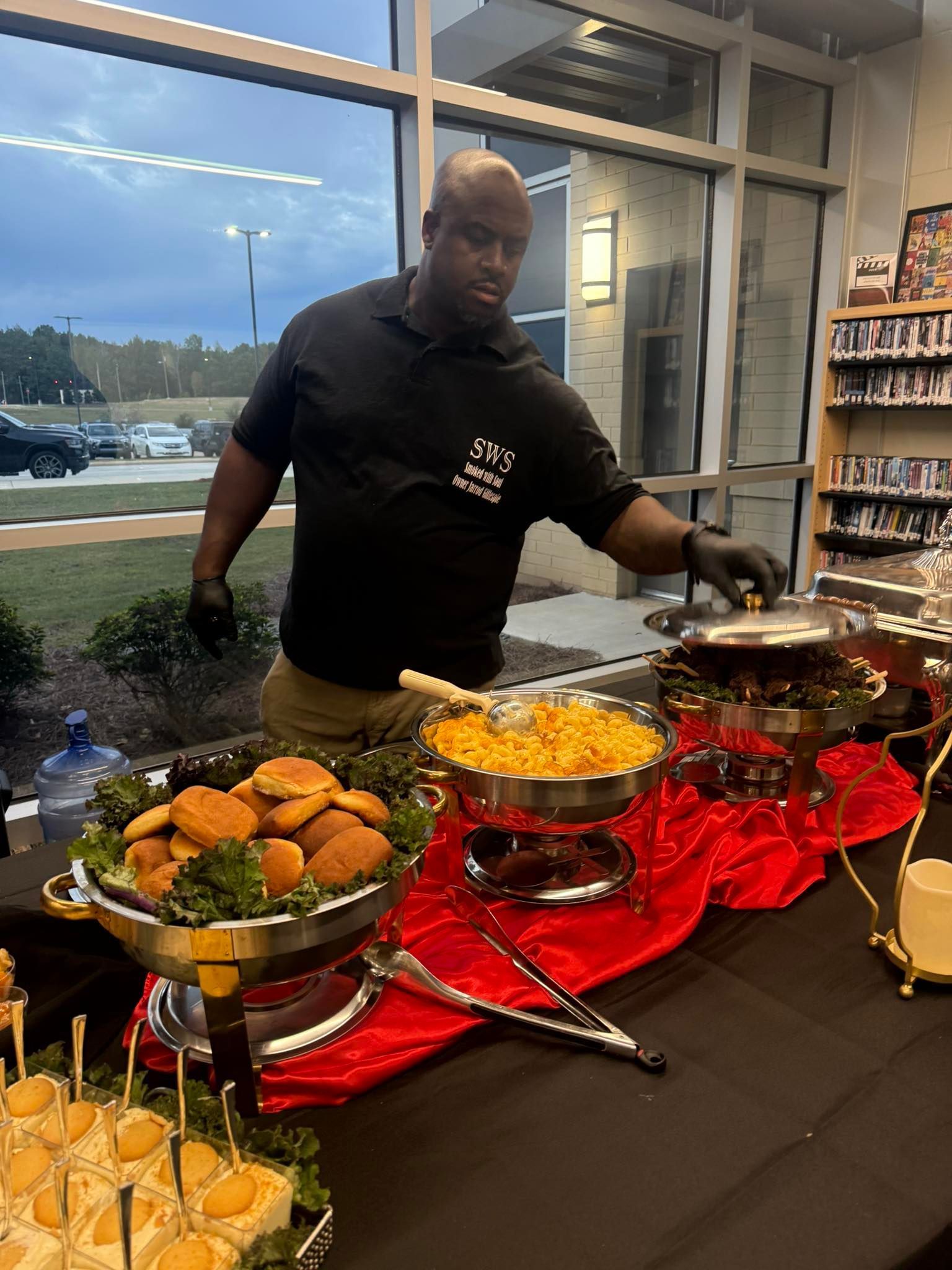 Man serving food from buffet table; includes fried food, pasta, and appetizers.