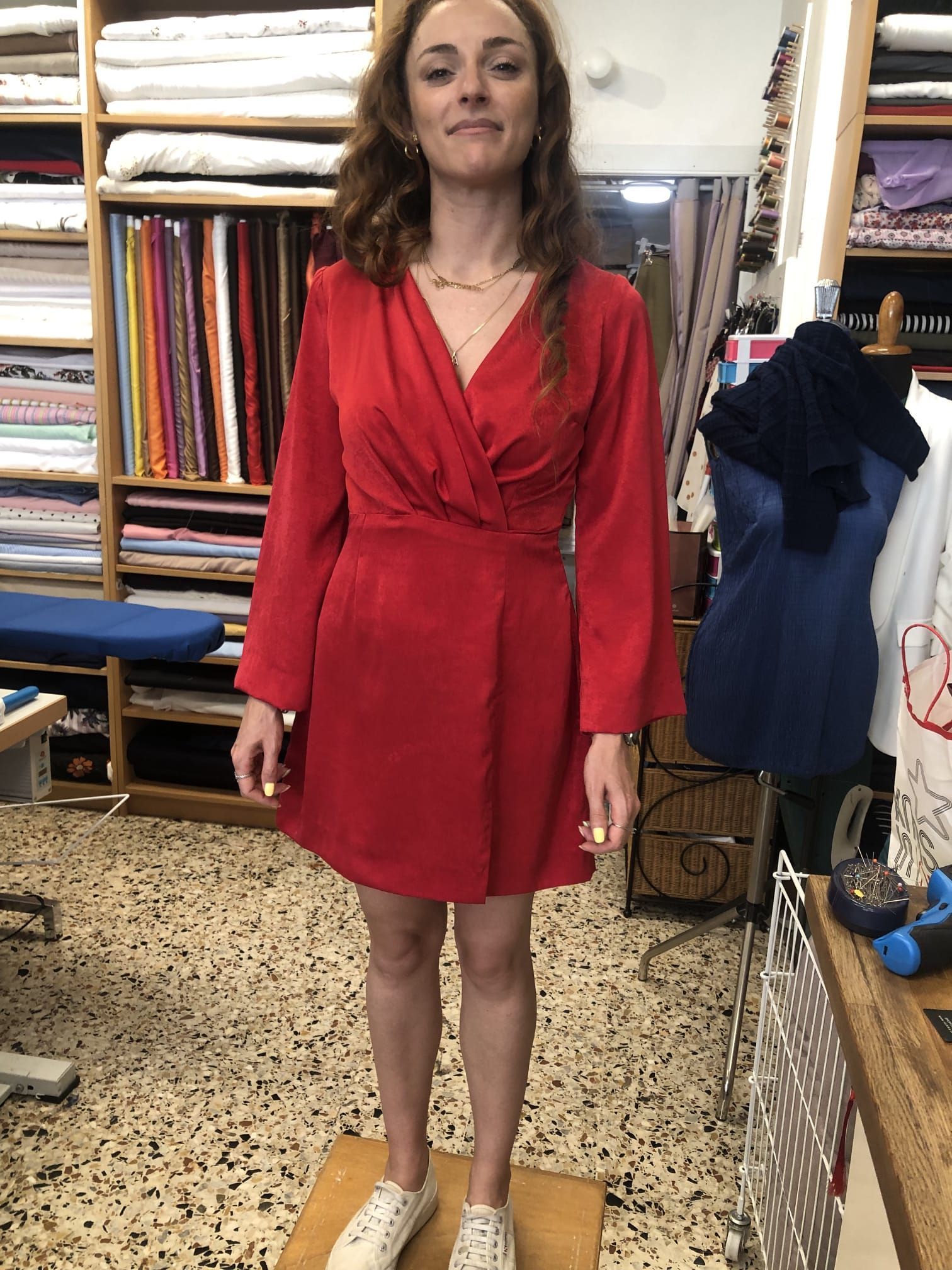 Interno del laboratorio Sartoria Luna con scaffali di filati, tessuti e strumenti artigianali ordinati con cura.