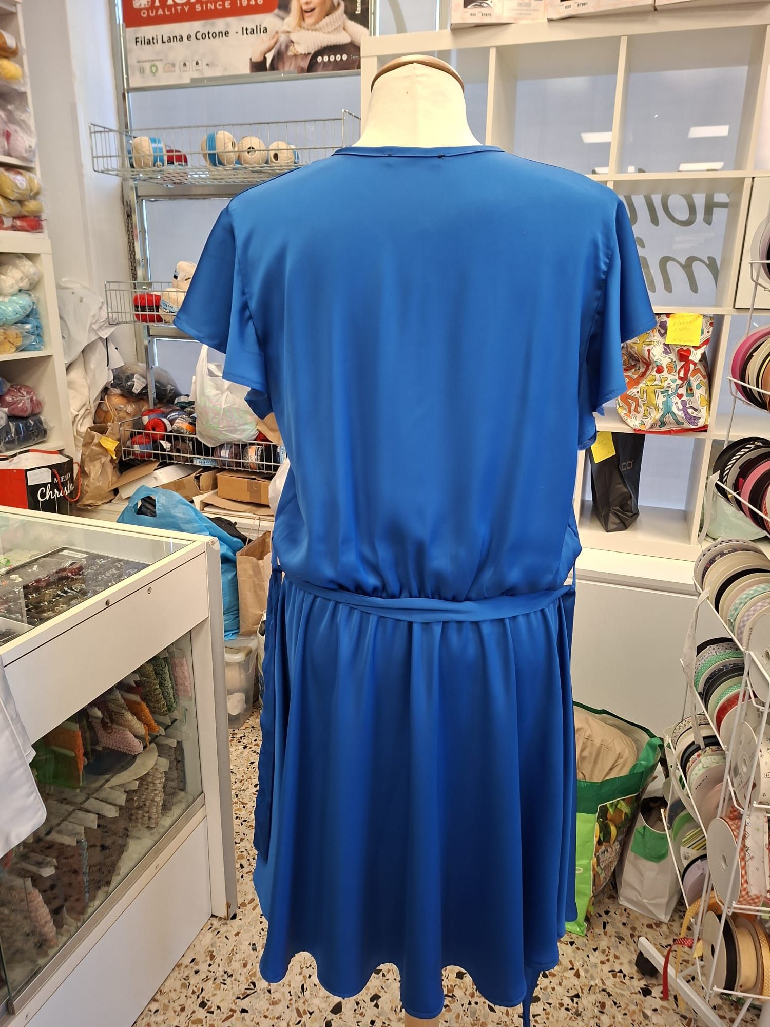 Banco di lavoro con fili, campionari tessili e strumenti di sartoria pronti per la lavorazione artigianale.