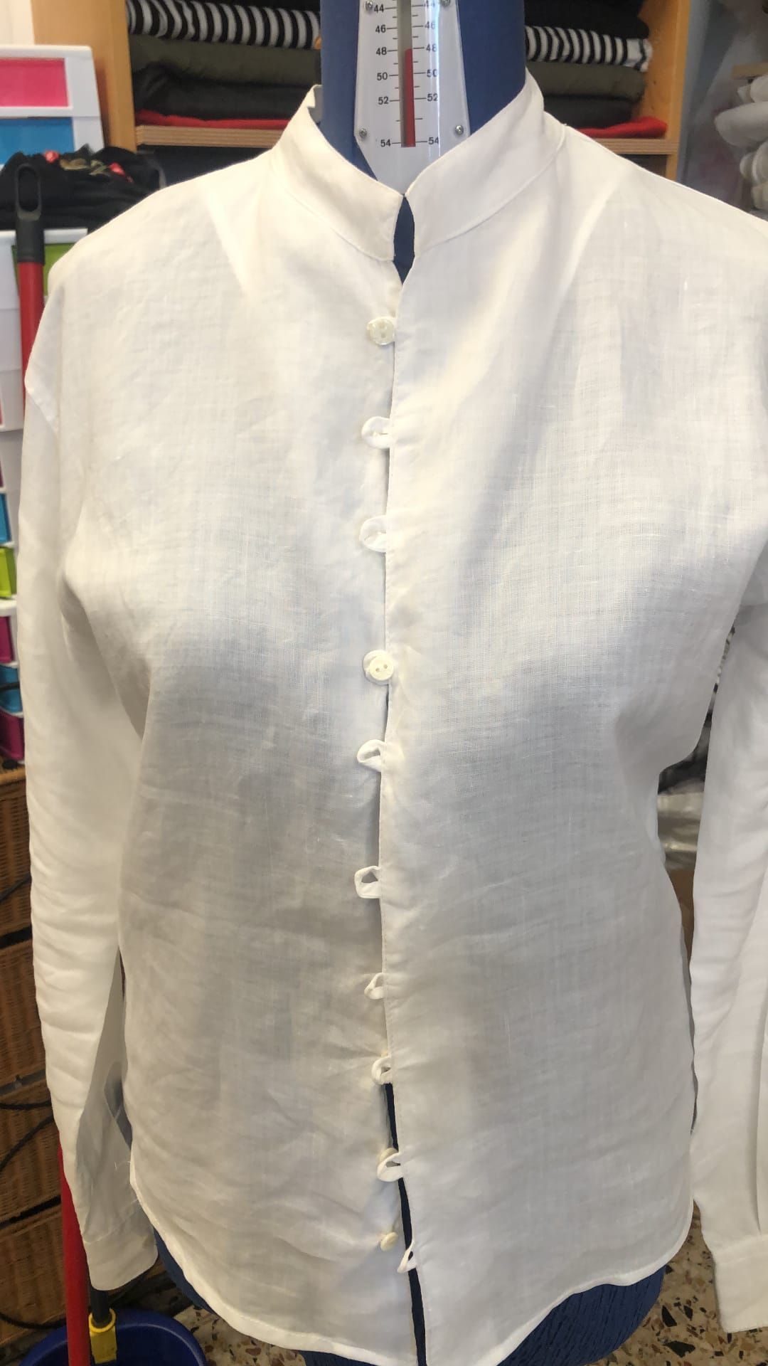 Sarto al lavoro con metro, forbici e tessuto nel laboratorio artigianale.