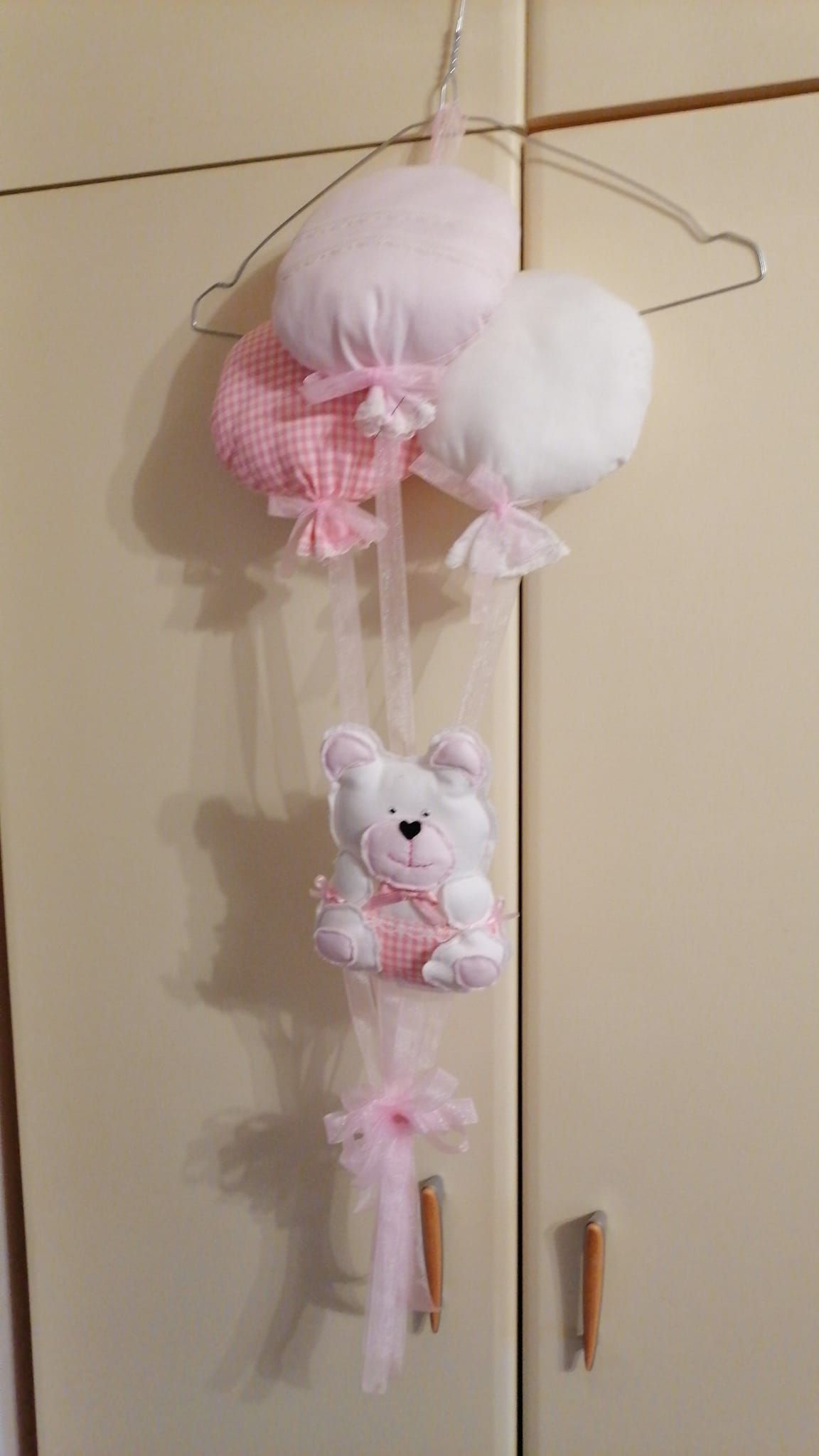 Una decorazione da parete raffigura tre palloncini di stoffa rosa e bianchi