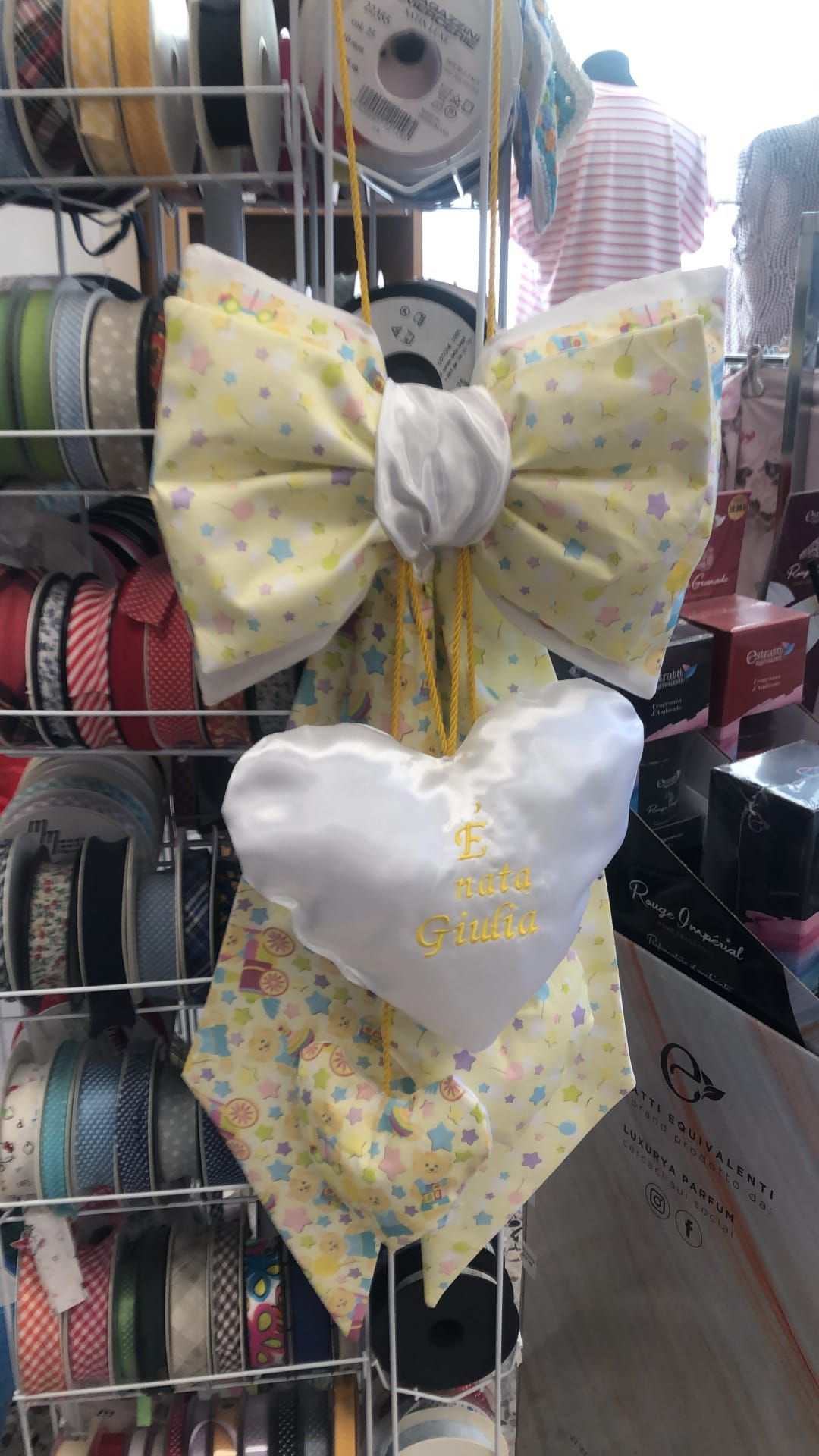 In una vetrina piena di nastri, un fiocco di stoffa giallo con una stampa a motivi geometrici pende 