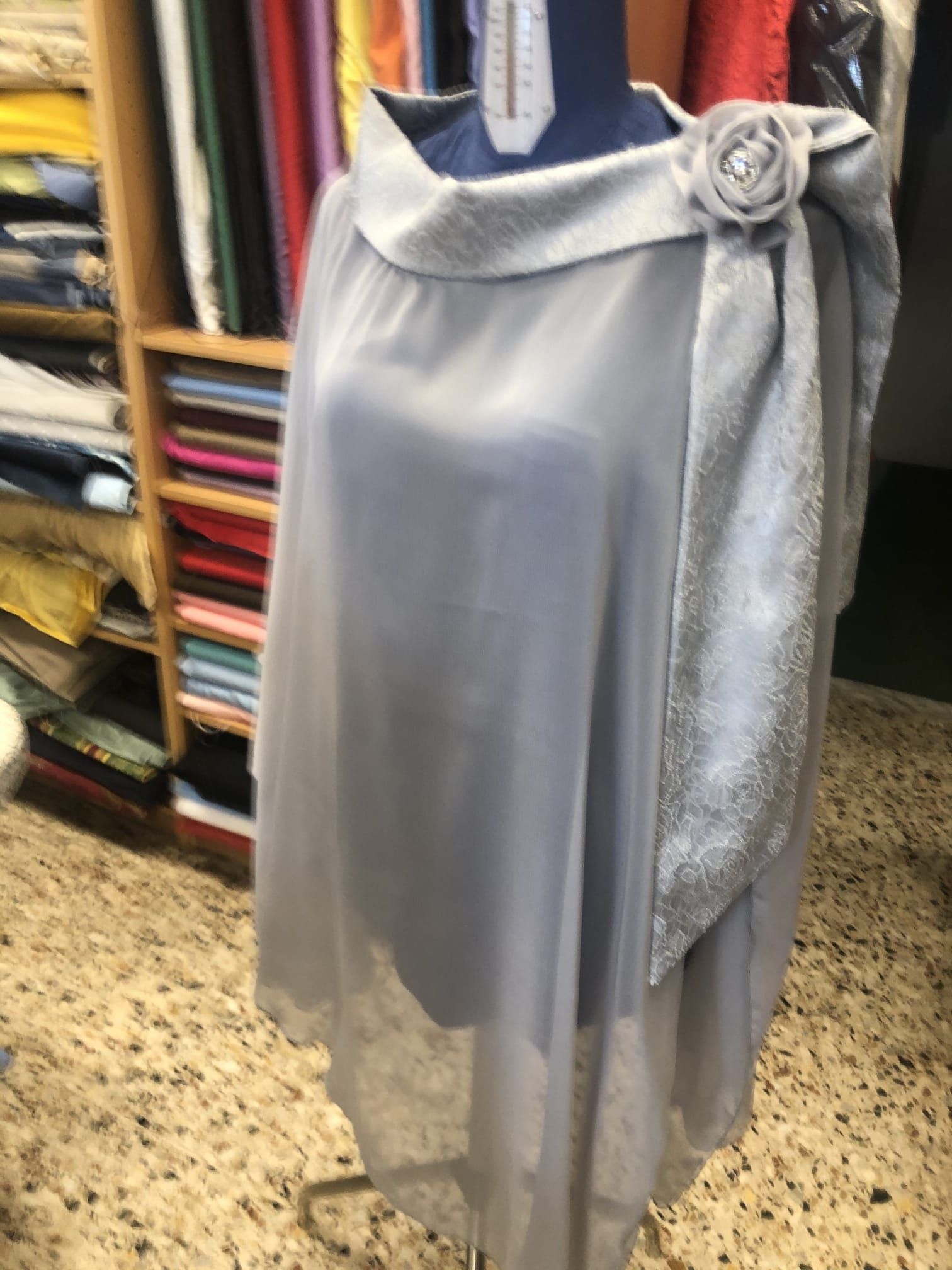 Interno del laboratorio Sartoria Luna con scaffali di filati, tessuti e strumenti artigianali ordinati con cura.