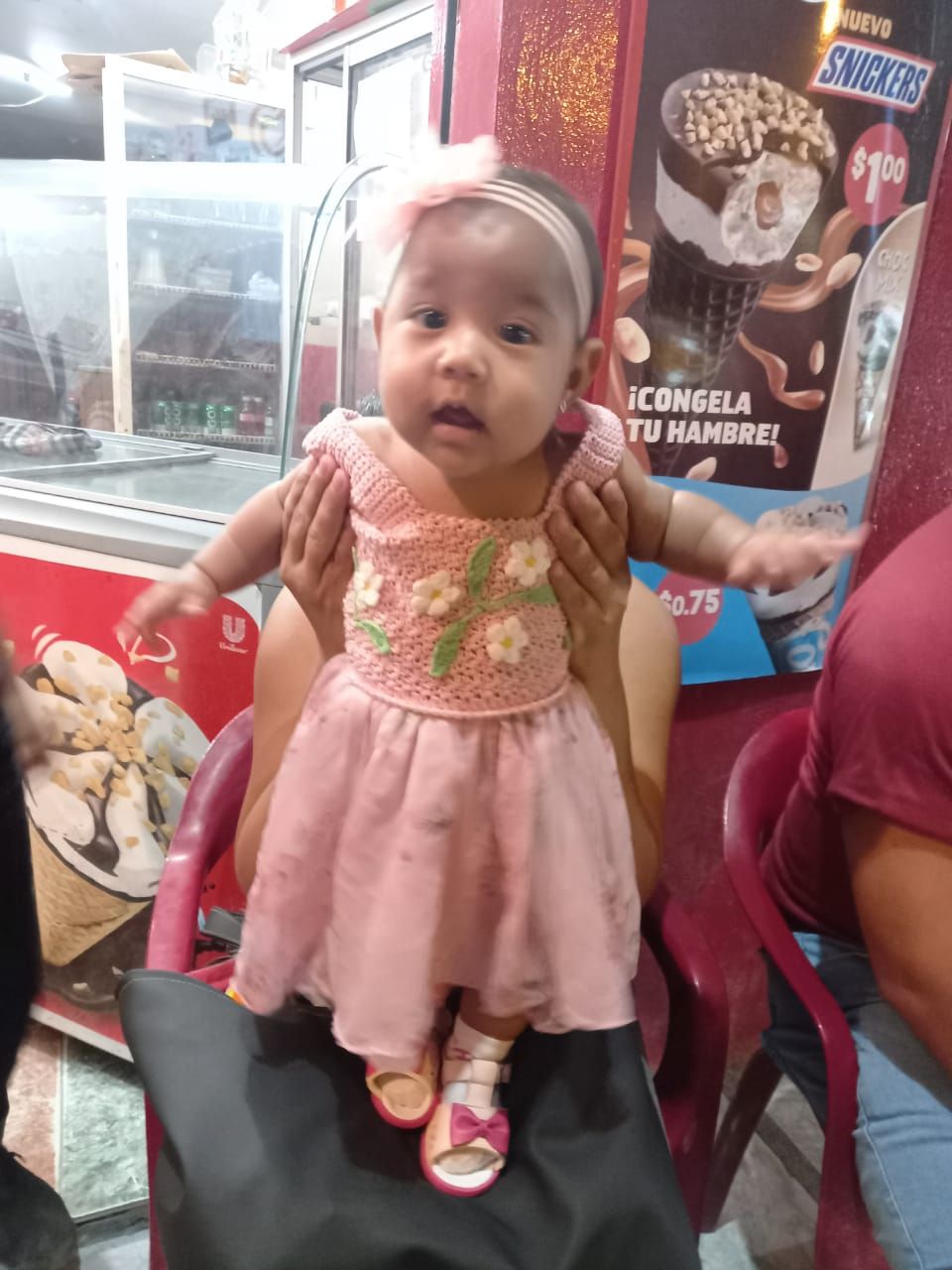 In un negozio, una bambina con indosso un vestitino rosa a fiori e una fascia per capelli