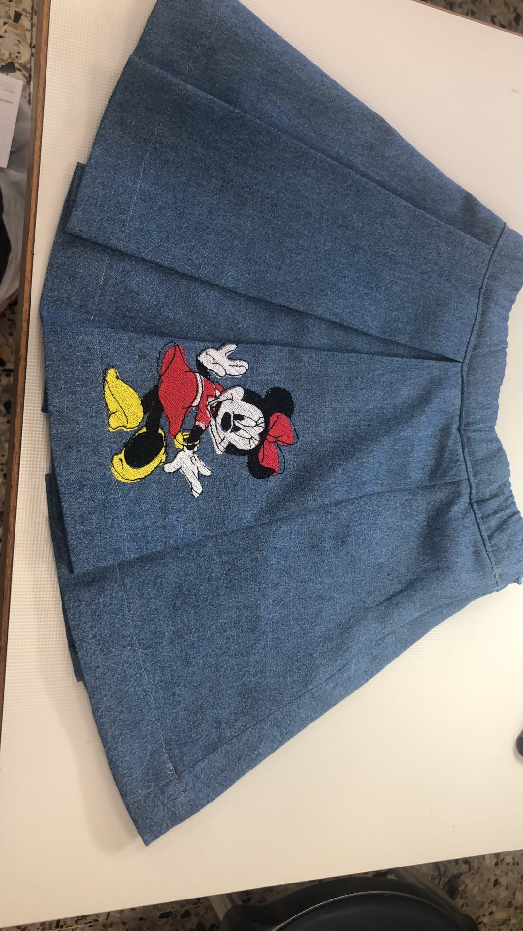 Banco di lavoro con fili, campionari tessili e strumenti di sartoria pronti per la lavorazione artigianale.