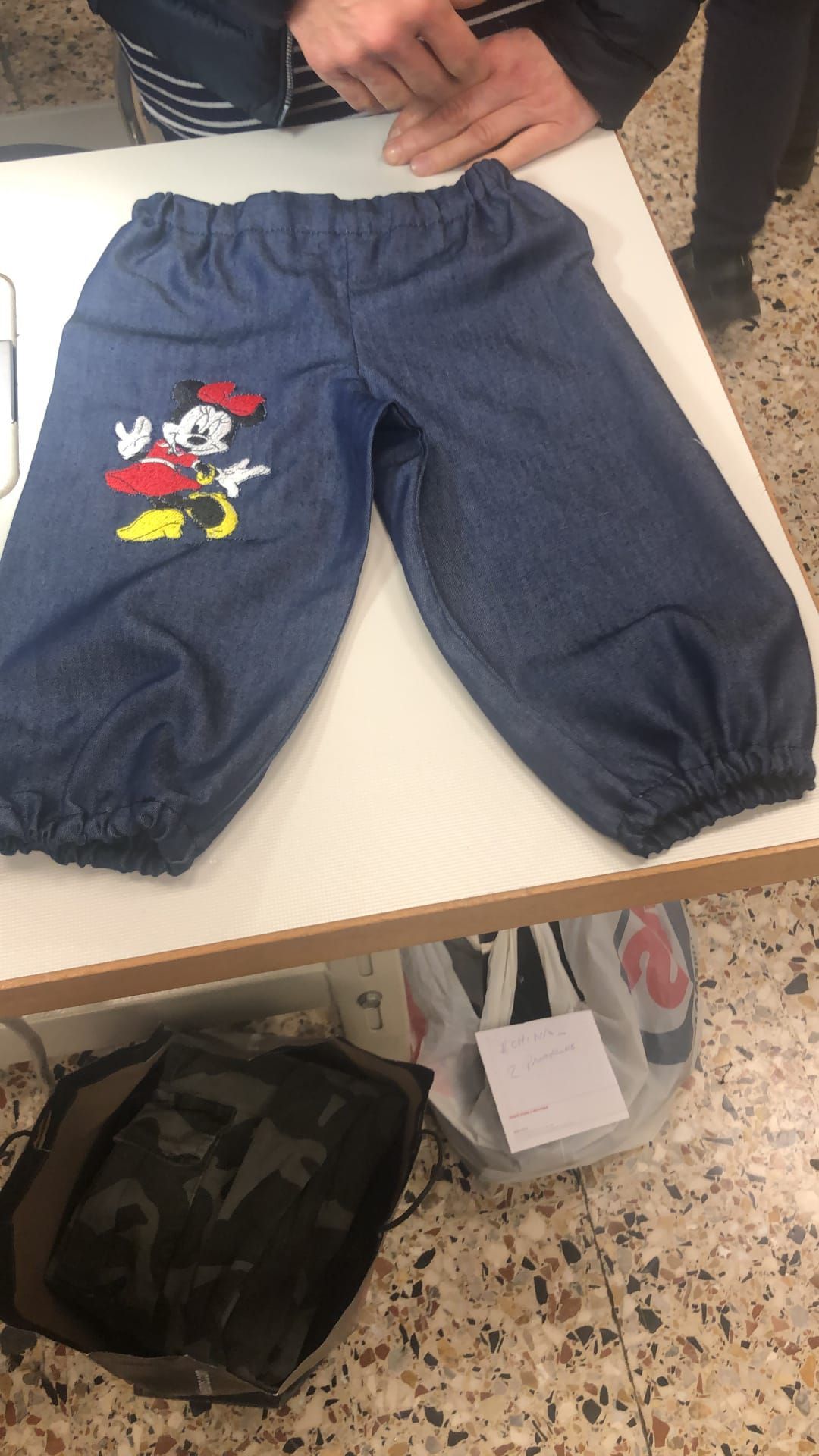 Interno del laboratorio Sartoria Luna con scaffali di filati, tessuti e strumenti artigianali ordinati con cura.