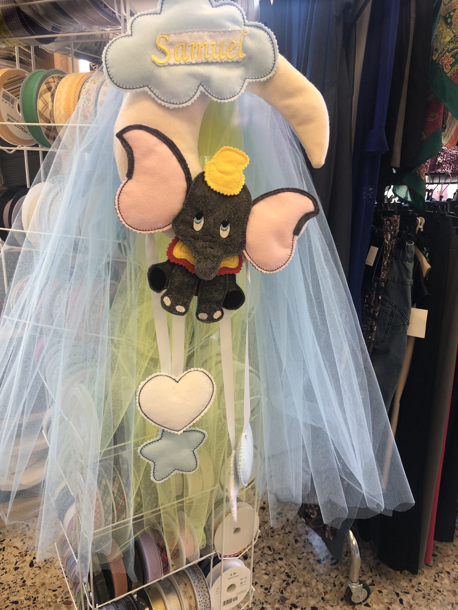 In un negozio, una giostrina per neonati a tema Dumbo, con un Dumbo in feltro