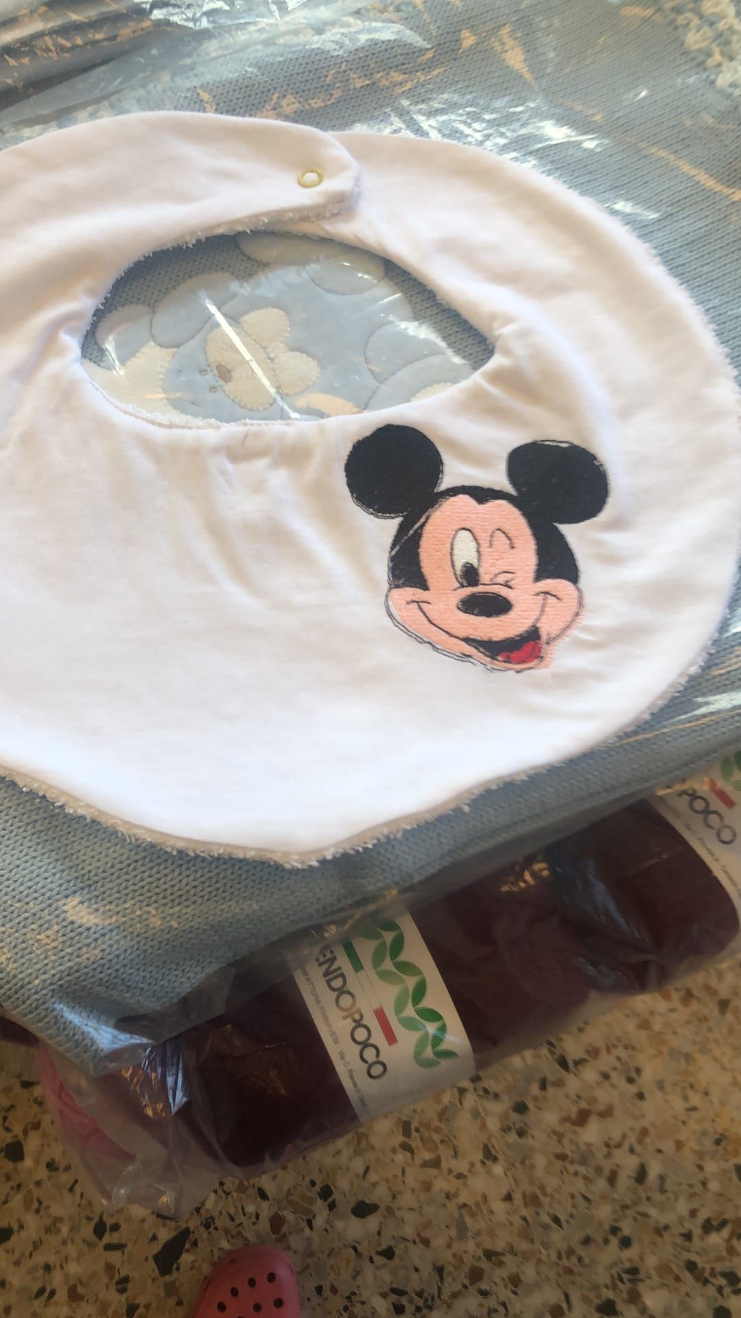 Un bavaglino bianco per neonati con l'immagine di Topolino che fa l'occhiolino