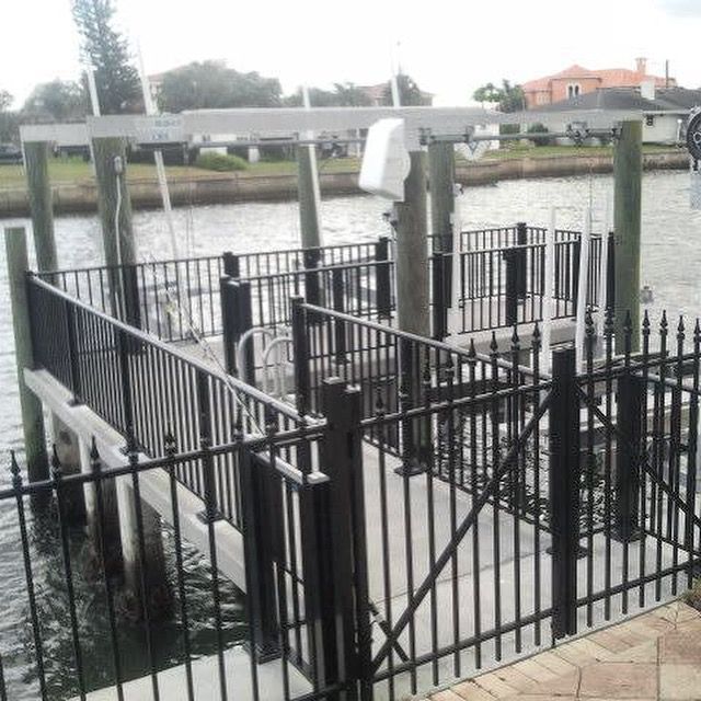 A boat lift with black railings on a concrete dock, next to water.