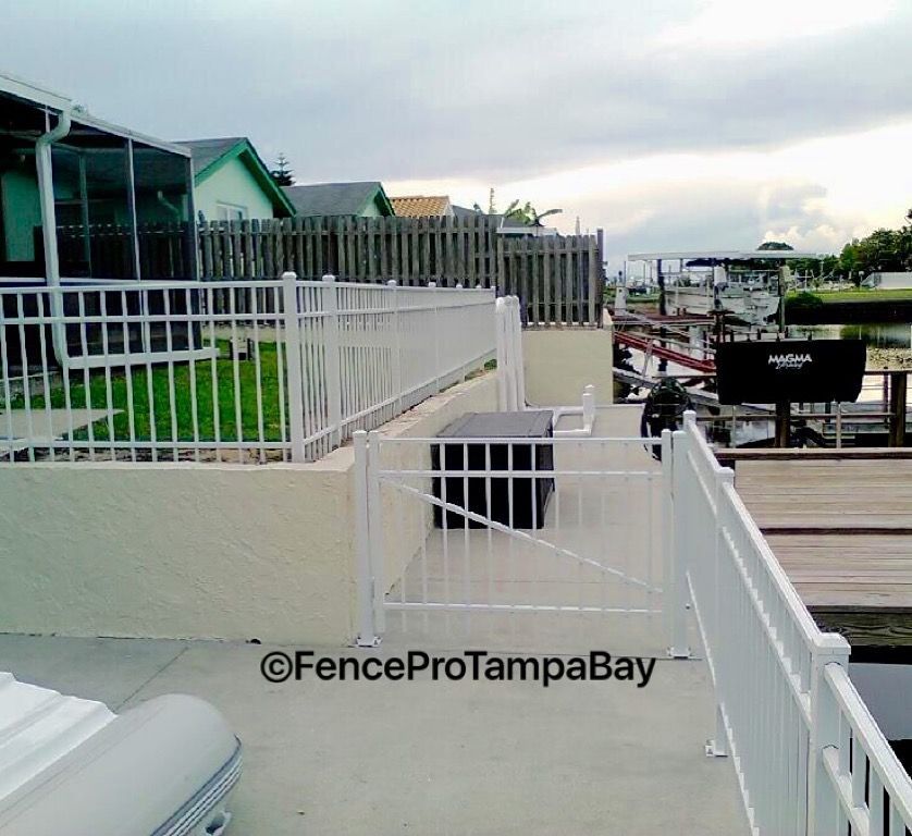 White metal fence near a waterfront property, providing safety and boundary.