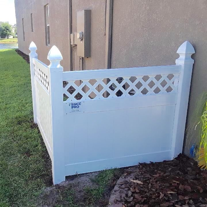 White vinyl fence surrounding an outdoor unit next to a light-colored house.