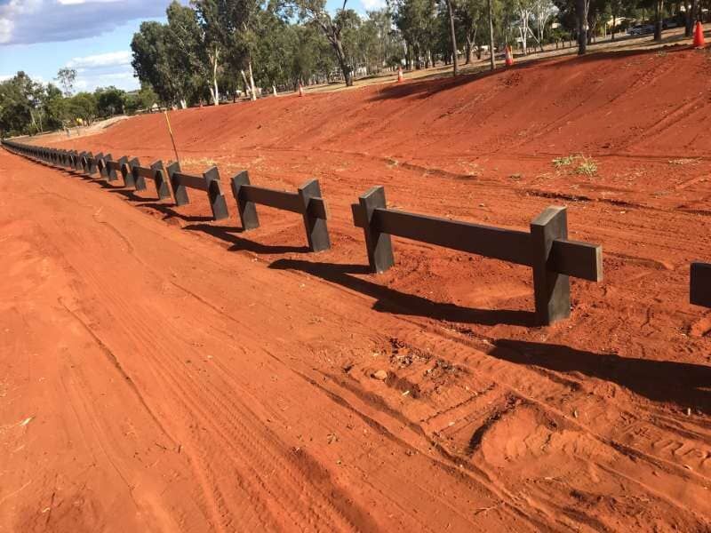 A Row Of Wooden Fences On A Dirt Road — Mulch, Fencing And Landscaping Mackay, QLD