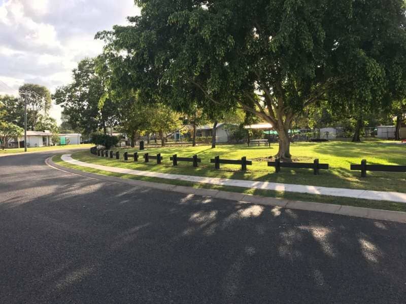 A Wooden Fence Surrounds A Park With Trees And Houses In The Background — Garden Maintenance And Mini Digger Hire In Mackay And Surrounds, QLD