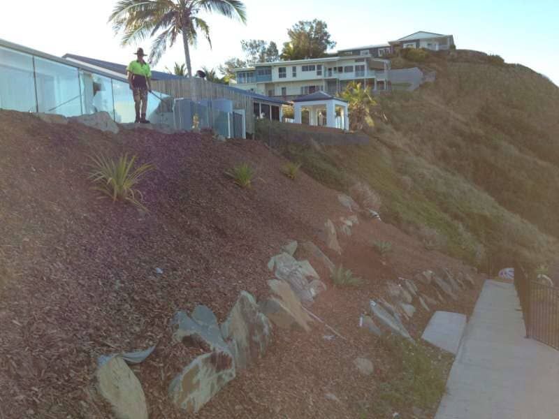 A Man Standing On Top Of A Hill With A House In The Background — We Supply And Pump Cypress Mulch, Tea Tree Mulch And More In Mackay, QLD