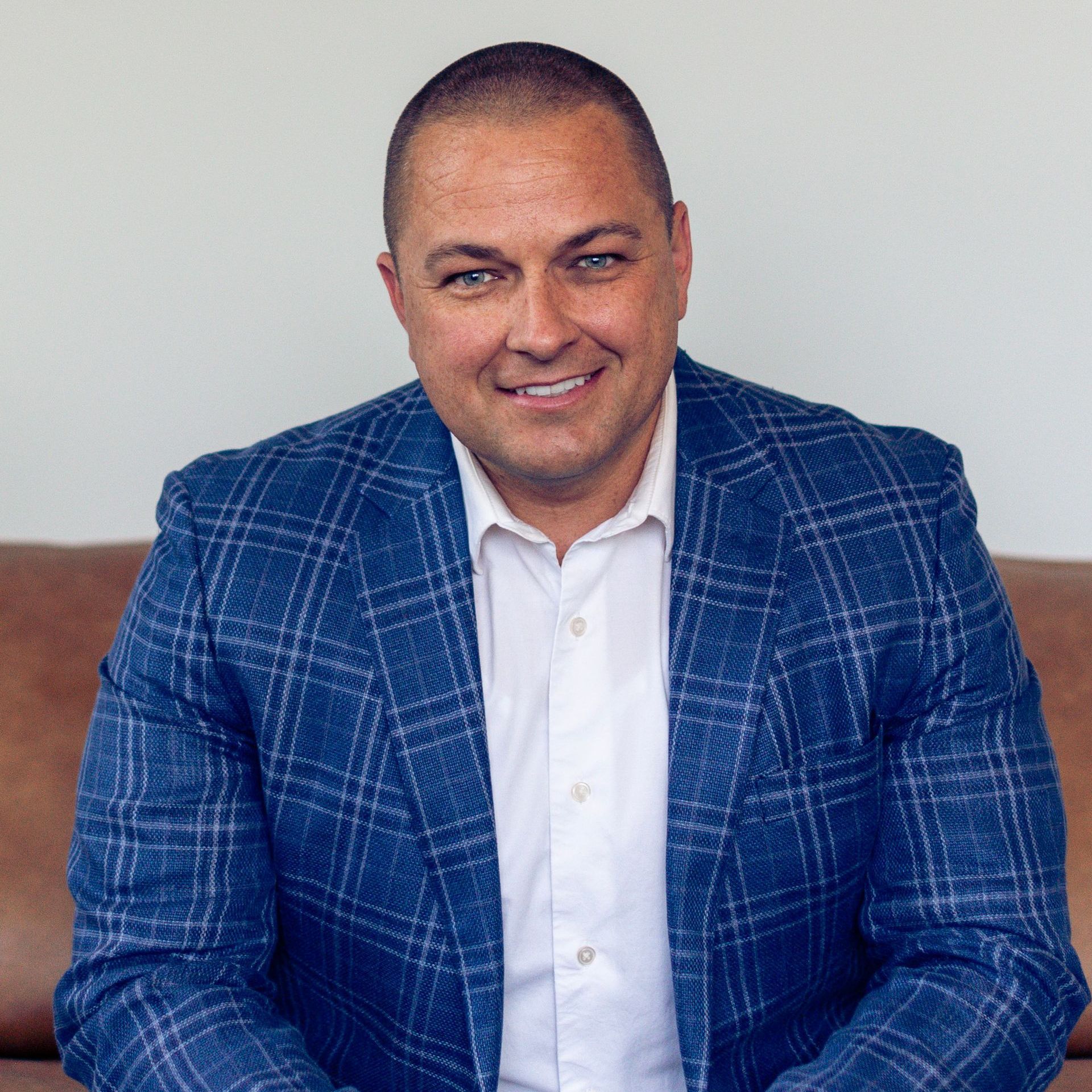 A man in a blue suit and white shirt is sitting on a couch.