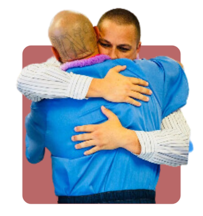 A man in a blue shirt is hugging another man in a white shirt