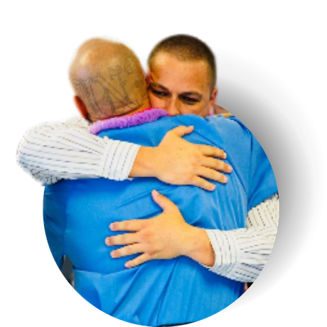 A man in a blue shirt is hugging another man in a white shirt