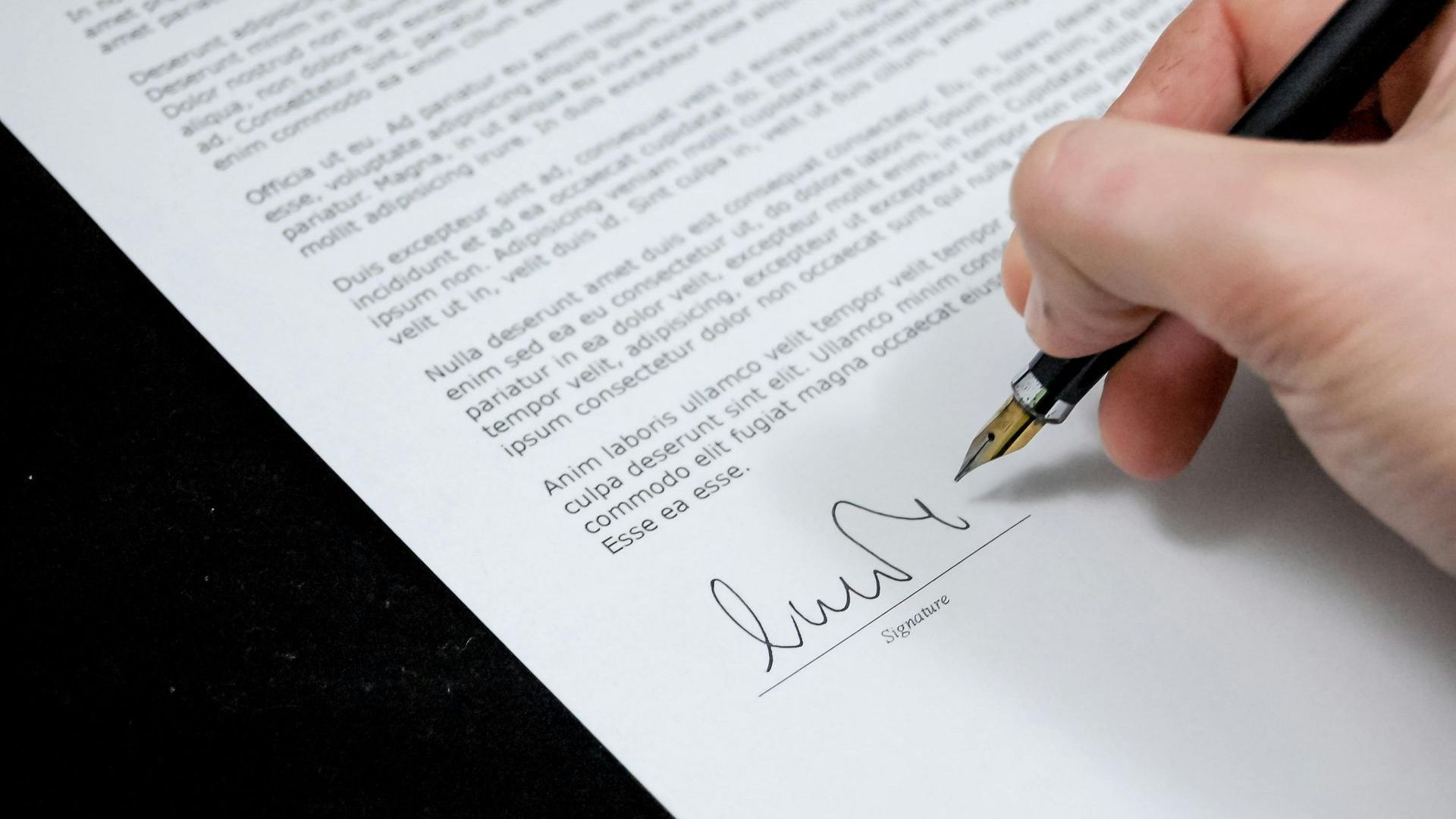 A person is signing a document with a fountain pen.