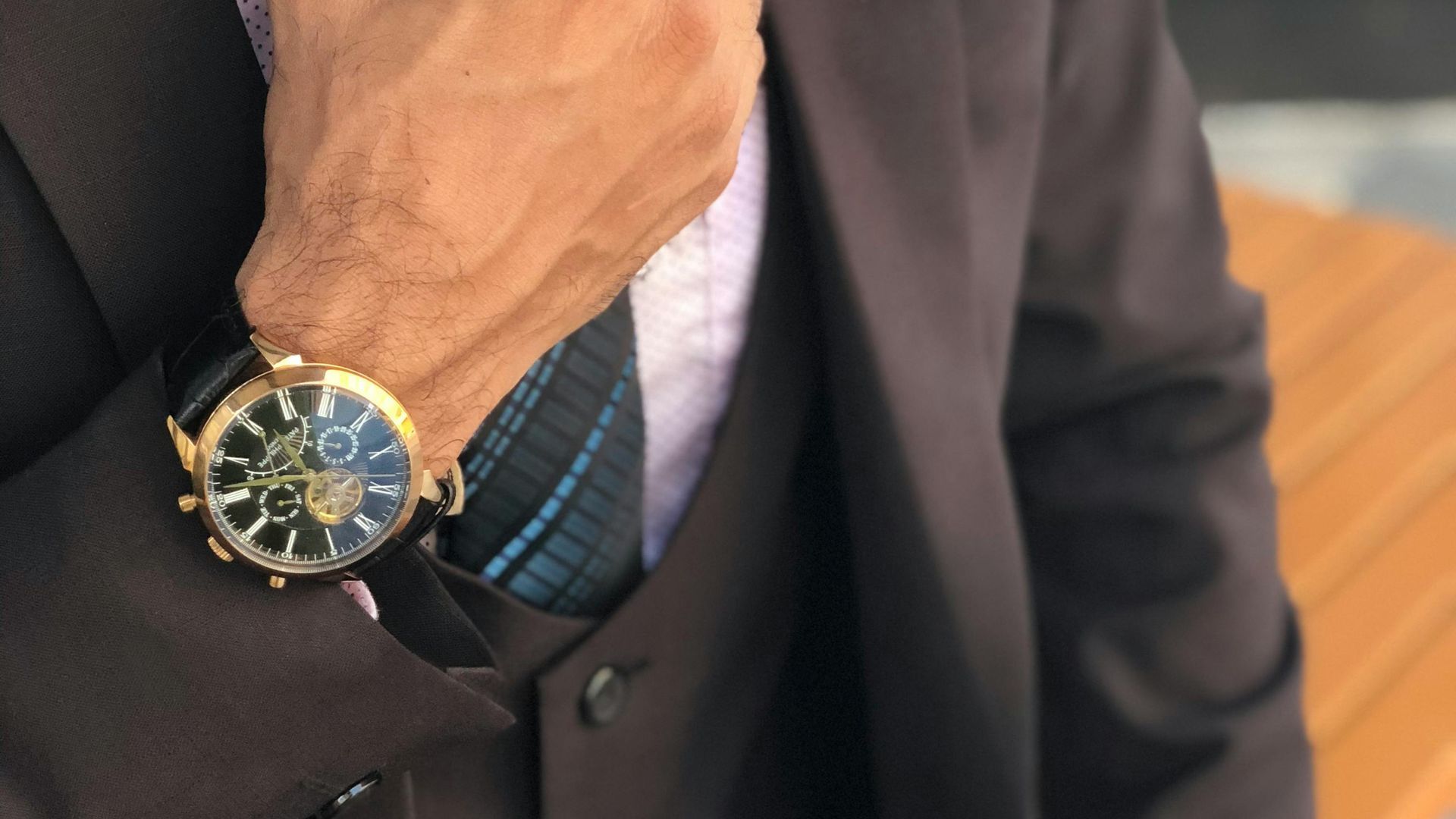 A man in a suit and tie is wearing a watch on his wrist.