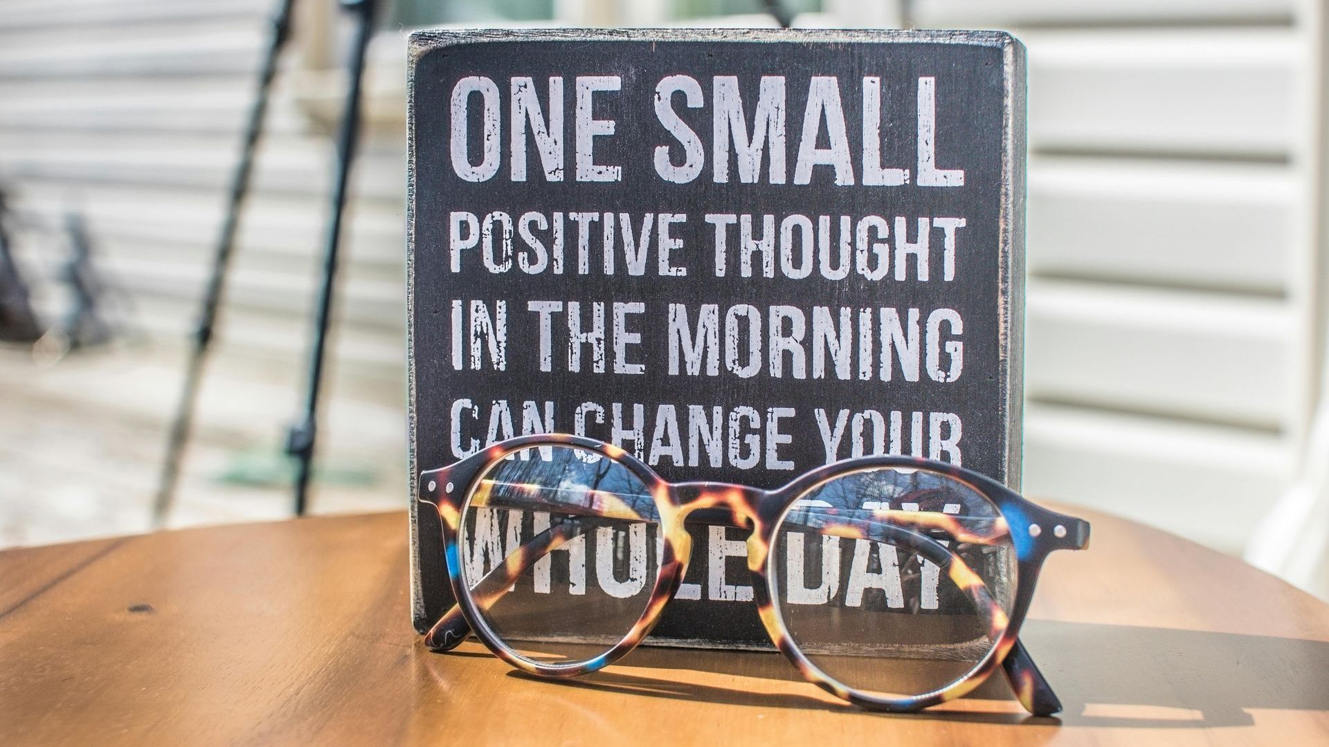 A sign that says `` one small positive thought in the morning can change your whole day '' next to a pair of glasses.