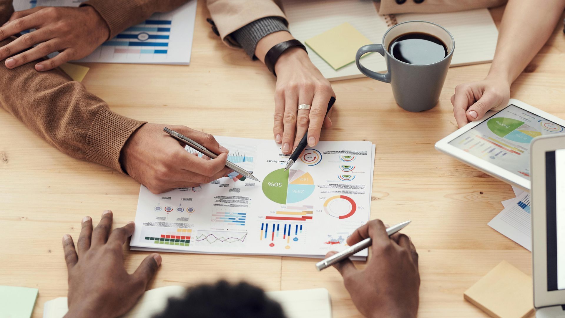 A group of people are sitting around a table looking at a pie chart.