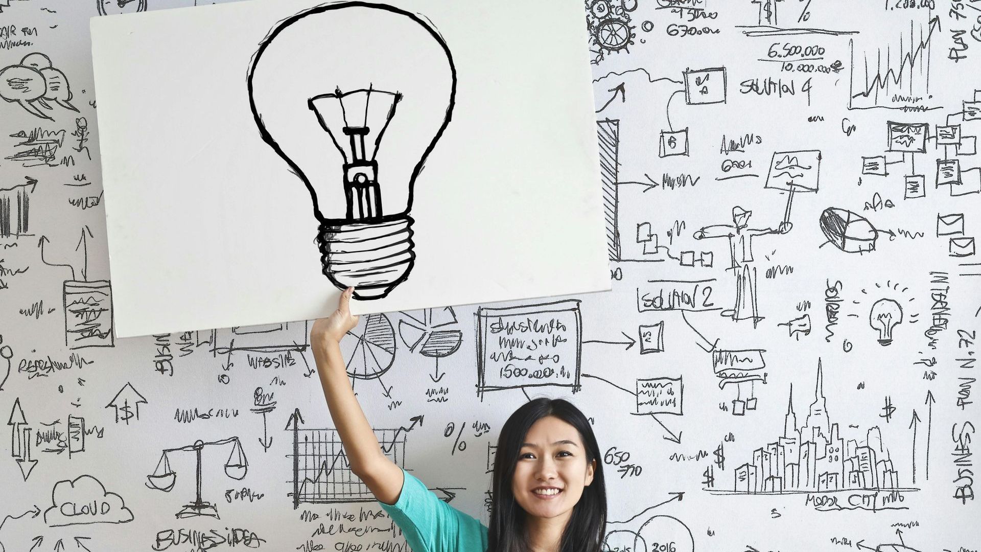 A woman is holding a sign with a light bulb drawn on it.