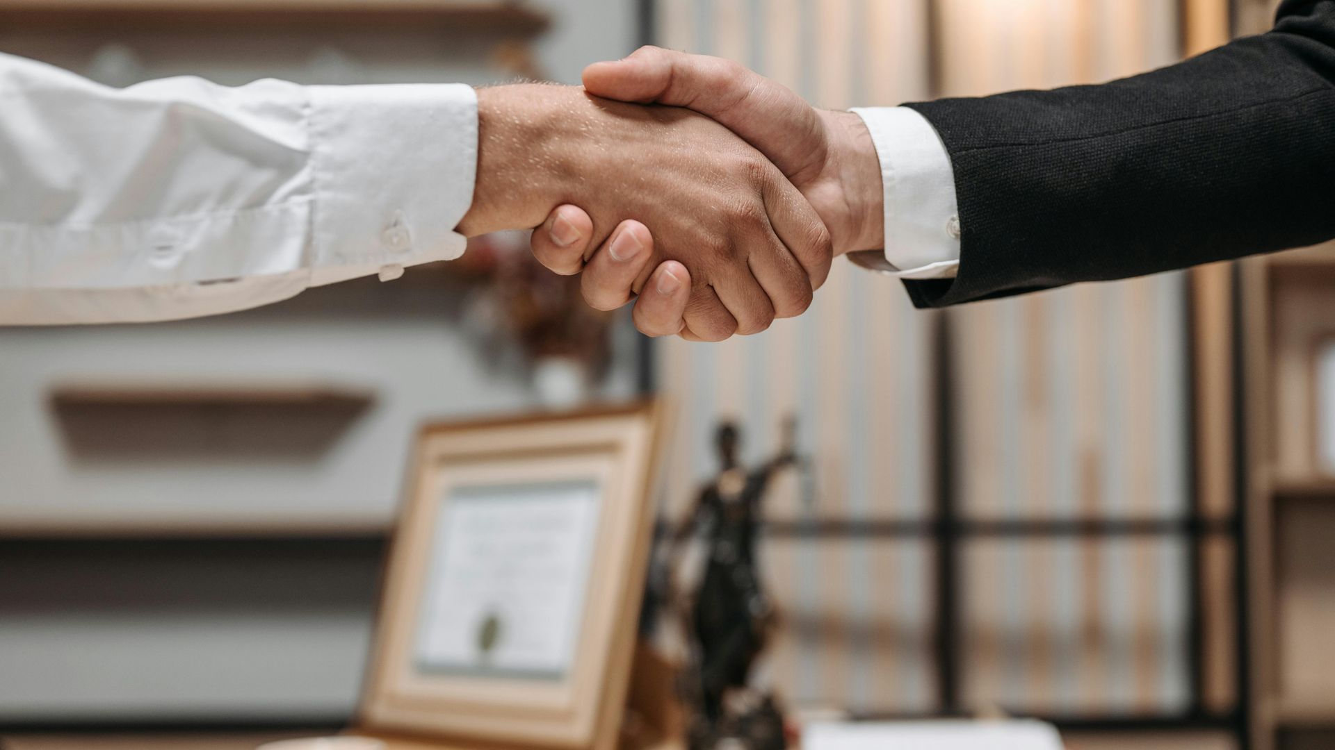 Two men are shaking hands in an office.