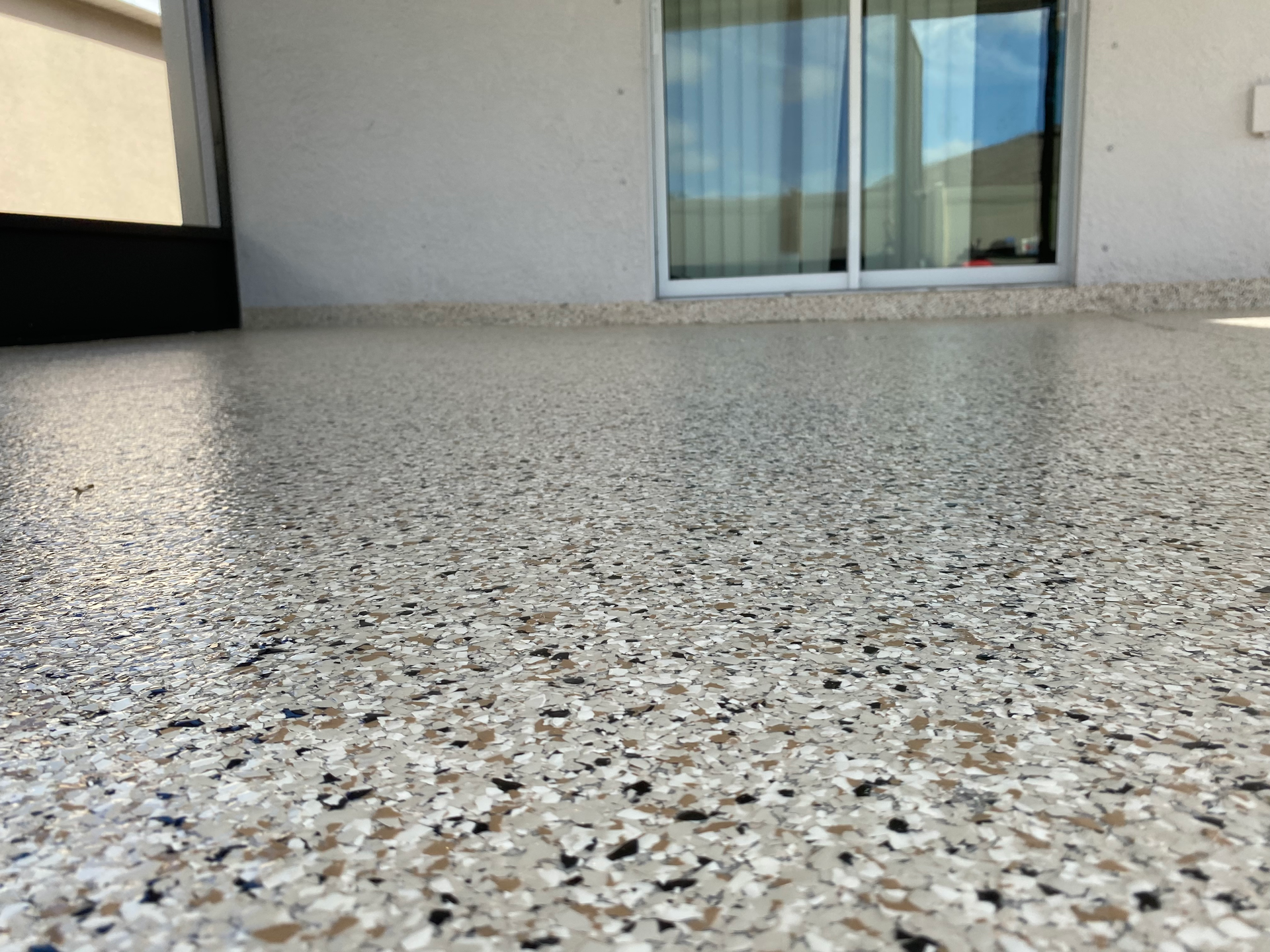 A patio with a concrete floor and a sliding glass door.